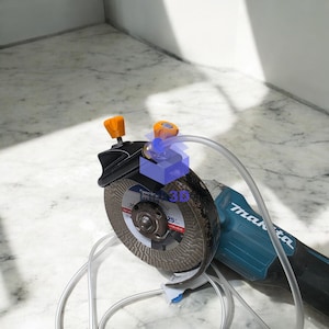 May include: A Makita angle grinder with a circular cutting blade. The tool is black and teal with orange adjustment knobs. A clear tube and a 3D graphic are also visible.