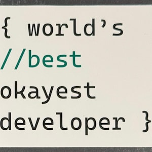 Op de afbeelding: Een witte kaart met zwarte tekst die luidt: { world's //best okayest developer }