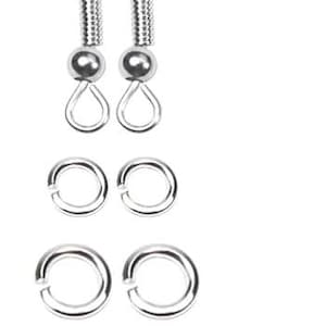 Puede incluir: Un conjunto de componentes de pendientes plateados, que incluye dos ganchos para pendientes, dos peque&ntilde;os anillos de salto, dos anillos de salto m&aacute;s grandes y dos topes transparentes para pendientes. Los componentes est&aacute;n dispuestos sobre un fondo blanco.