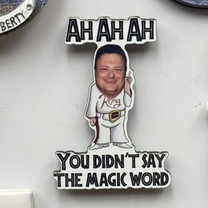 May include: A novelty magnet featuring a cartoon image of a man in a white outfit with the text "AH AH AH" above his head and "YOU DIDN'T SAY THE MAGIC WORD" below. The man is pointing upwards.