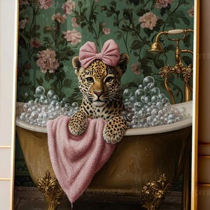 May include: A leopard cub with a pink bow on its head sits in a gold clawfoot bathtub filled with bubbles. A pink towel hangs over the edge of the tub. The background features a green wall with a floral pattern and a gold faucet fixture.
