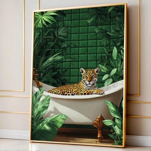 May include: A framed art print featuring a jaguar relaxing in a white bathtub. The jaguar has a spotted coat and is surrounded by lush green foliage and a green tile wall. The artwork is framed in a gold-colored frame.