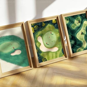 Puede incluir: Tres impresiones artísticas enmarcadas de campos de golf. Cada impresión presenta una vista aérea diferente de un hoyo de golf, con calles verdes, trampas de arena y golfistas. Los marcos son de madera clara y la obra de arte tiene un estilo de acuarela.