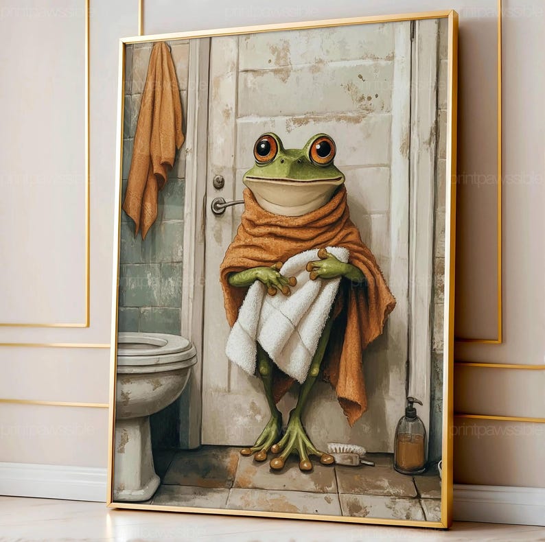 May include: A framed art print depicts a green frog in a bathroom setting. The frog is wrapped in an orange towel and holding a white towel. The bathroom includes a toilet, a door, and a soap dispenser. The art has a vintage, whimsical style.