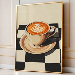 May include: A framed art print featuring a coffee cup with latte art. The cup and saucer are beige, set against a black and white checkered background. The coffee has a heart-shaped design. The frame is gold.