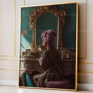 May include: A framed print featuring a woman in a leopard print robe and a purple head wrap, seated at a vanity table. The vanity has a mirror with ornate gold detailing, and the background is teal with floral accents. The print is in a gold frame.
