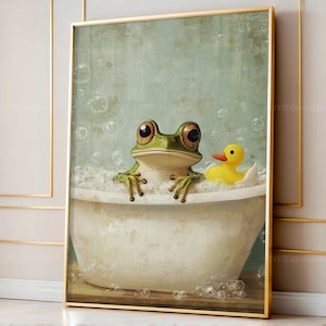 May include: A framed print depicts a green frog with large brown eyes in a white bathtub filled with bubbles. A yellow rubber duck sits in the tub. The background is a light teal color with bubbles floating around the frog and duck.