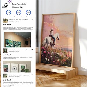 May include: A framed art print shows a person on a white horse in a field of wildflowers under a sunset. The artwork is displayed on a wooden stand, creating a rustic feel. The print has a light wooden frame, adding to its charm.