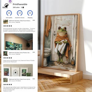May include: A framed bathroom art print featuring a cartoon frog wrapped in a towel and wearing a shawl. The frog stands in front of a bathroom door. A towel hangs on the door. The print is displayed on a wooden stand.