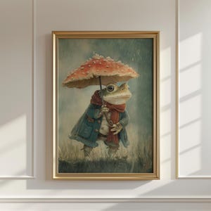 May include: A framed art print featuring a whimsical frog character. The frog is dressed in a blue coat and red scarf, holding a mushroom umbrella. The artwork has a vintage, storybook aesthetic, with a muted color palette and a rainy background.