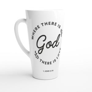 Op de afbeelding: Witte latte mok met een gebogen handvat. De mok heeft de tekst "WHERE THERE IS God THERE IS LOVE" in een cirkelvormig ontwerp, met de bijbelverwijzing 1 Johannes 4:16.