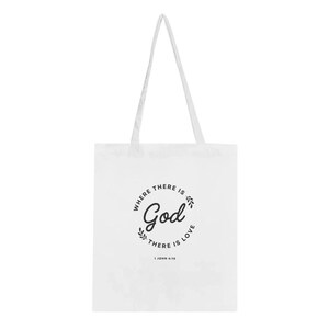 Op de afbeelding: Witte draagtas met lange handvatten. De tas heeft de tekst "WHERE THERE IS GOD THERE IS LOVE" in een cirkelvormig ontwerp met een bladerenrand. De tekst "1 JOHN 4:16" staat eronder.