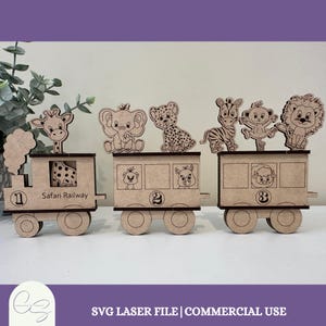 May include: A wooden Safari Railway train set with three carriages. The first carriage is a locomotive with a giraffe and the text "Safari Railway." The other carriages feature animal cutouts: an elephant, cheetah, zebra, monkey, and lion. Each carriage has a number.