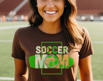 May include: A brown t-shirt with a green and brown graphic that says "Soccer Mom" with a football in the middle of the word "Mom".
