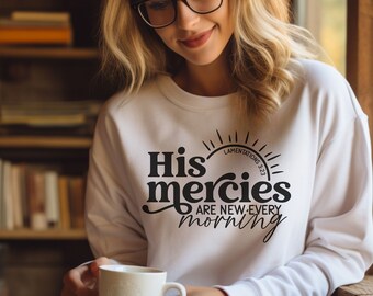 May include: White sweatshirt with black text that reads "His mercies are new every morning" with a sun graphic and the text "Lamentations 3:23".