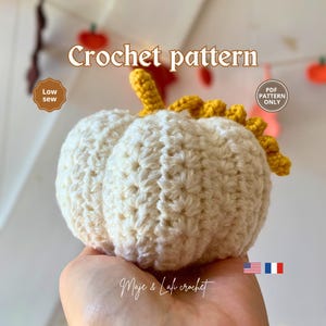 Peut inclure: Une citrouille crochetée crème avec une tige jaune. Le texte "Crochet pattern" est en haut. Les mots "Low sew" et "PDF pattern only" sont également visibles. Le nom de la boutique Etsy "Maje & Lafi crochet" est en bas.