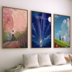 May include: Three framed movie posters with a white sofa and a coffee table in front of them. The posters are of the film "Howl's Moving Castle". The first poster shows a pink and green landscape with a young woman and a man walking in the distance. The second poster shows a blue sky with a shooting star and a moon. The third poster shows a green field with a young woman and a man walking in the distance.