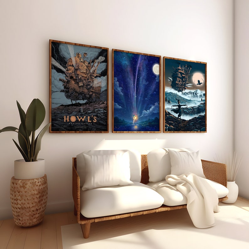 May include: Three framed movie posters on a white wall above a white couch with a white throw blanket. The posters are of the animated films Howl's Moving Castle, Spirited Away, and Kiki's Delivery Service. The posters are all in a similar style with a dark background and a light colored image.