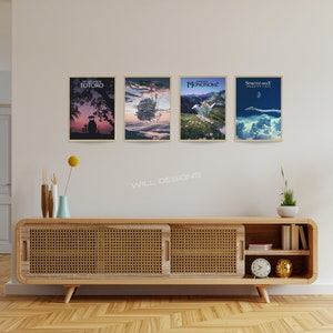 May include: Four framed art prints with movie-themed illustrations hang on a white wall. The prints feature colorful scenes with text. A wooden cabinet with a woven front and decorative items sits below the artwork. The room has a warm, inviting atmosphere.