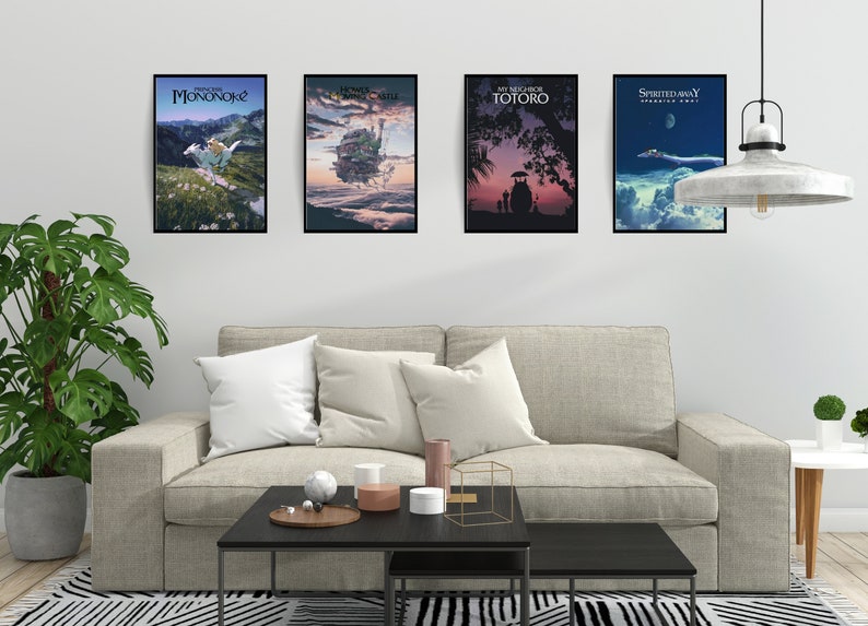 May include: Four framed movie posters hang above a beige sofa. The posters feature artwork from animated films, including "Princess Mononoke," "Howl's Moving Castle," "My Neighbor Totoro," and "Spirited Away."