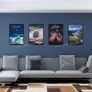 May include: Four framed movie posters hang on a blue wall above a gray sectional sofa. The posters feature artwork from animated films, including "Spirited Away," "Howl's Moving Castle," "My Neighbor Totoro," and "Princess Mononoke."