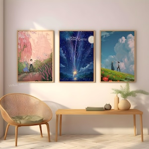 May include: Three framed prints of scenes from the animated film Howl's Moving Castle. The first print shows a pink and green landscape with a castle in the background. The second print shows a blue night sky with a shooting star and the text "Howl's Moving Castle". The third print shows a green field with a couple walking towards a red poppy.