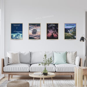 May include: Four framed movie posters with gold frames are displayed on a white wall. The posters feature artwork from animated films, including "Spirited Away," "Castle in the Sky," "My Neighbor Totoro," and "Princess Mononoke." A white sofa with pillows sits below the posters.