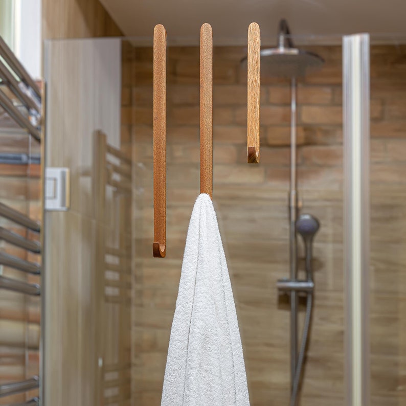 A towel hanging on the wooden hook which is easily and simply attached over a shower cabin glass.