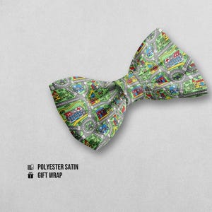 Può includere: Un papillon in raso di poliestere con un divertente design a mappa stradale in verde, grigio, rosso, giallo e blu. Il motivo presenta strade, edifici e rotatorie. È visibile anche il testo "POLYESTER SATIN GIFT WRAP".