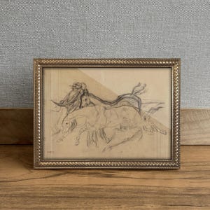 Puede incluir: Un boceto a lápiz enmarcado de caballos en movimiento. La obra de arte está en un marco dorado con un borde texturizado. El boceto representa varios caballos corriendo, con un fondo claro.
