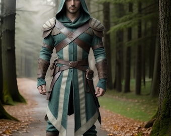 Könnte beinhalten: Ein Mann trägt eine grüne und weiße Tunika mit Kapuze und braunen Lederapplikationen und einem Gürtel. Er steht in einer Waldlandschaft.