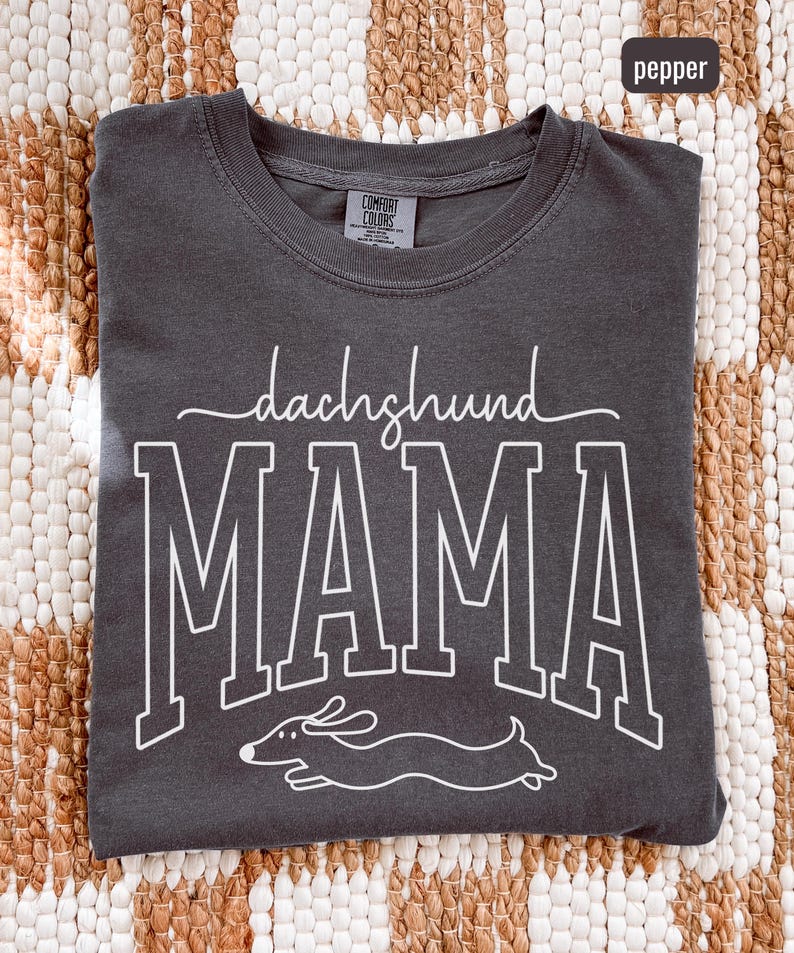 May include: Pepper-colored Comfort Colors t-shirt with the words "dachshund MAMA" in white, along with a line drawing of a dachshund. The shirt has a crew neck and short sleeves.