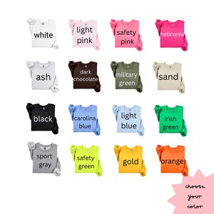 May include: A range of long-sleeved sweatshirts in colours such as white, light pink, safety pink, heliconia, ash, dark chocolate, military green, sand, black, carolina blue, light blue, irish green, sport grey, safety green, gold, and orange. Each shirt has a colour label.