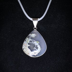Peut inclure: Un collier avec un pendentif en argent et une pierre d'agate en forme de larme. La pierre présente un motif blanc, gris et vert.