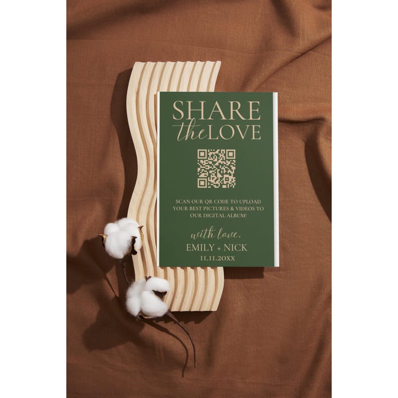 Op de afbeelding: Een groene kaart met de tekst "SHARE the LOVE" in gouden letters. Een QR-code bevindt zich in het midden van de kaart. De tekst onder de QR-code luidt: "SCAN OUR QR CODE TO UPLOAD YOUR BEST PICTURES & VIDEOS TO OUR DIGITAL ALBUM! with love. EMILY + NICK 11.11.20XX"