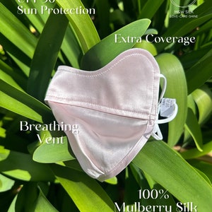 May include: A light pink silk face mask with a breathing vent and UPF 50+ sun protection. The mask is made of 100% mulberry silk and has extra coverage. The text "M&W SILK LOVE-CARE-SHINE" is printed on the mask.