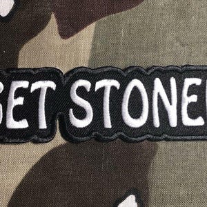 Puede incluir: Parche bordado en blanco y negro con el texto "GET STONED" en letras blancas sobre fondo negro.