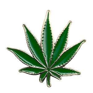 May include: A green marijuana leaf pin with gold accents. The pin is made of metal and has a shiny finish.