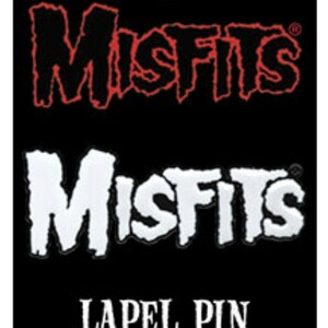 May include: A black and white lapel pin with the word "Misfits" in a bold, stylized font. The pin is a collectible for fans of the band Misfits.