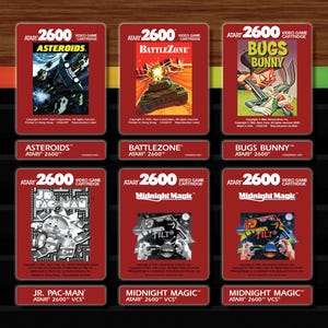 Puede incluir: Una colección de cartuchos de videojuegos Atari 2600. Los cartuchos rojos presentan títulos de juegos como Asteroids, Battlezone, Bugs Bunny, Jr. Pac-Man y Midnight Magic. Cada cartucho muestra el título del juego y la marca Atari.