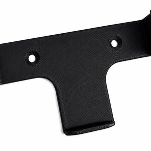 May include: A black T-shaped wall mount bracket with a textured surface. The bracket features two circular screw holes on the horizontal bar and a small upward-facing lip on the bottom vertical section to hold items securely in place.