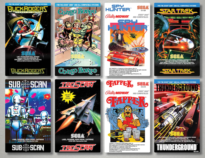 Pu&ograve; includere: Raccolta di scatole di cartucce per videogiochi SEGA vintage. I titoli includono "Buck Rogers", "Congo Bongo", "Spy Hunter", "Star Trek", "Sub Scan", "Tac Scan", "Tapper" e "Thunderground". Ogni scatola presenta opere d'arte colorate e titoli di giochi.