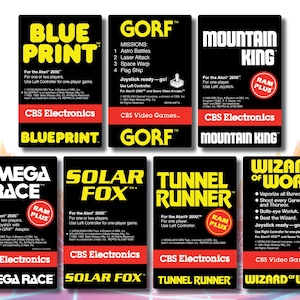 May include: A collection of Atari 2600 video game cartridges. Titles include "Blueprint," "Gorf," "Mountain King," "Omega Race," "Solar Fox," "Tunnel Runner," and "Wizard of Wor." Each cartridge features unique artwork and game details.