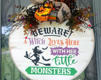 Beware which lives here with her little monsters wooden round sign