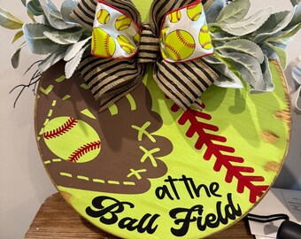At the ball field with the softball wooden round sign