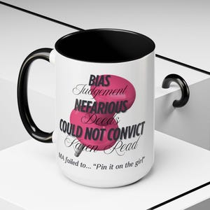 Puede incluir: Una taza de cerámica blanca con asa e interior negros. La taza presenta el texto "BIAS Judgement NEFARIOUS Deeds COULD NOT CONVICT Karen Read" en negro y rosa, con la frase "MA failed to... 'Pin it on the girl'" en la parte inferior.