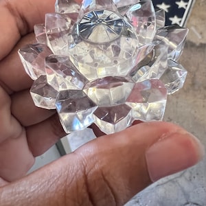 Puede incluir: Una escultura de flor de loto de cristal transparente con un diseño facetado. La escultura está hecha de cuarzo transparente y tiene un acabado liso y pulido.