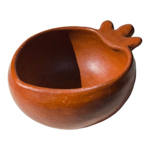 Könnte beinhalten: Eine Terrakotta-Schale mit einem einzigartigen Griff in Form einer Hand. Die Schale ist tief rotbraun und hat eine glatte, leicht strukturierte Oberfläche.