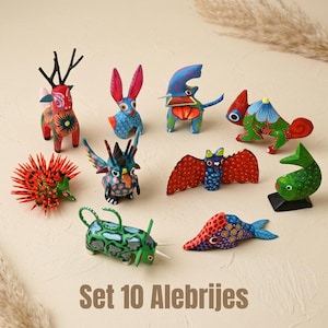 Puede incluir: Un conjunto de diez figuras de madera alebrijes pintadas a mano que representan varios animales, incluyendo un ciervo, conejo, erizo, murciélago y peces. Cada pieza muestra colores vibrantes y patrones detallados. El texto Set 10 Alebrijes es visible.