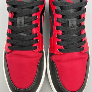 Puede incluir: Par de zapatillas rojas, negras y blancas. Las zapatillas tienen tela roja en la puntera y los paneles laterales, revestimientos de cuero negro y cordones negros. La leng&uuml;eta y el cuello son negros, con un logotipo rojo en la leng&uuml;eta.